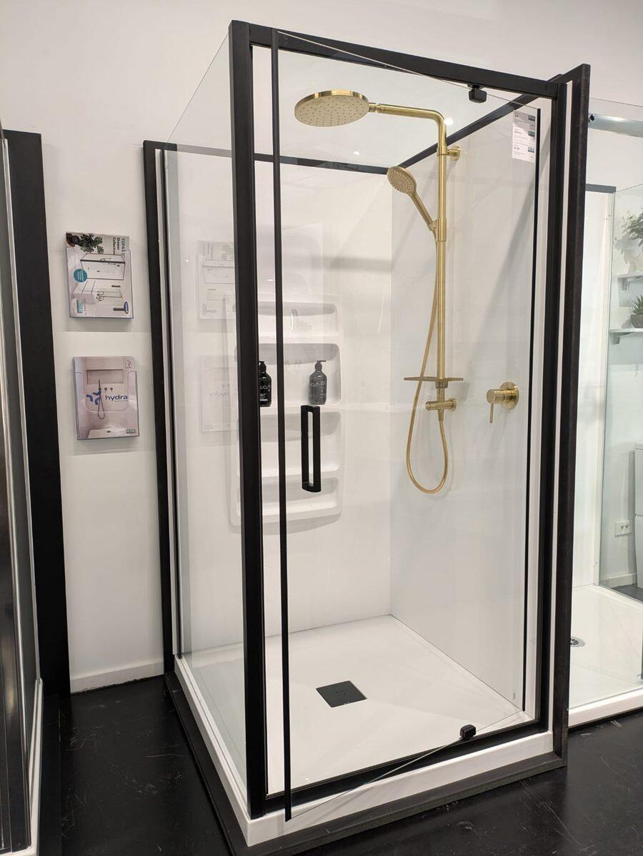 Black framed shower enclosure with a brushed gold shower column