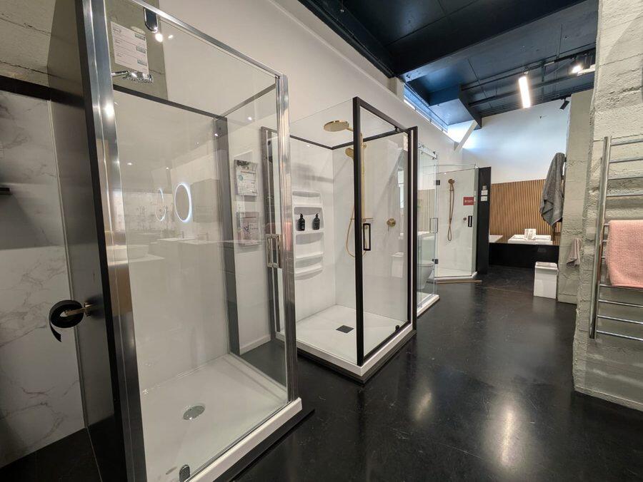 Shower enclosures on display, including framed and sliding door options