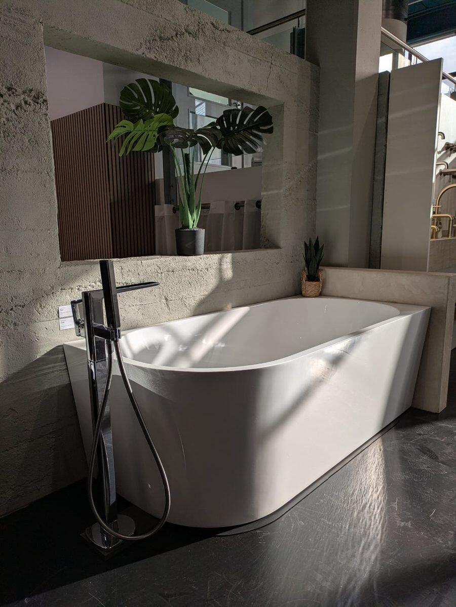 A freestanding bath on display with a floor mounted bath mixer