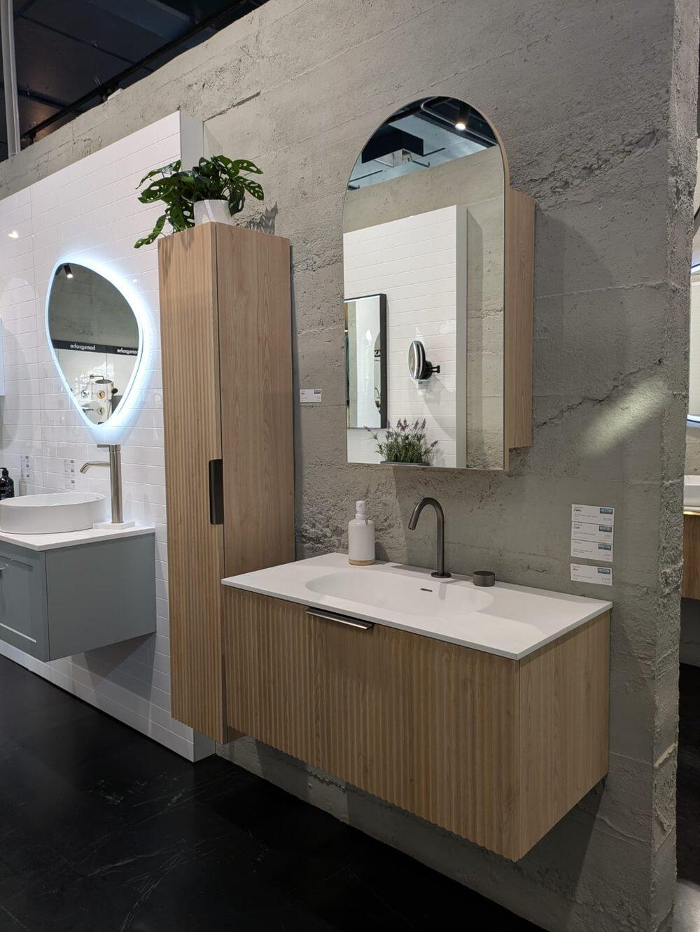 A room setting in the showroom with a timber vanity, arch mirror and tall cabinet