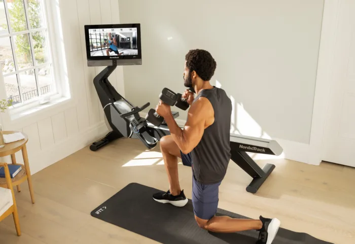 man working out with dumbbells next to the rw900 rower